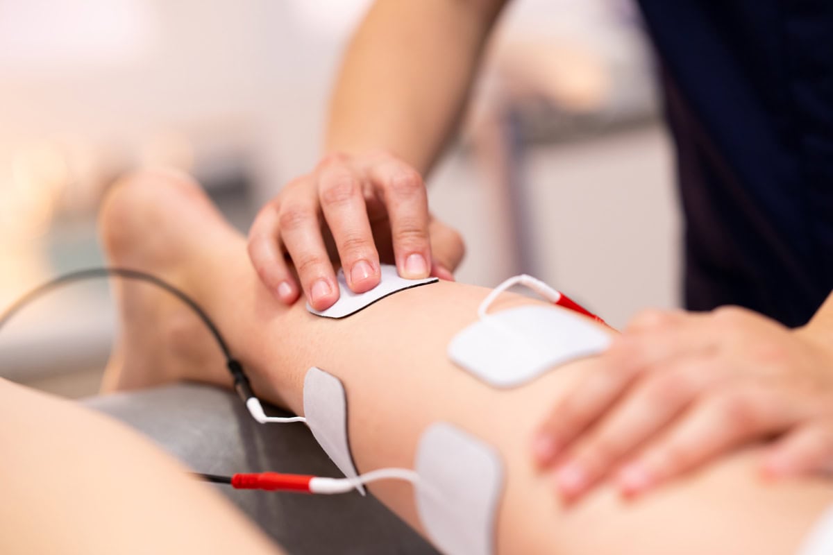 Das Bild zeigt eine Elektrostimulation bei einem jungen Patienten während einer Behandlung zur Muskelstärkung.